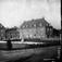 Damplassen, Ullevål Hageby, Oslo. 1925. Bebyggelse med forretninger i bakgrunnen. Beplantning i forgrunnen.