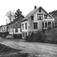 Næs på Kleive. ,  Bilde fra Nes sentrum. I det hvite huset til høyre holdt Karl Ludvik Vatne til, han drev med daglivarer og fiskemat. I huset ved siden av var konfeksjonsfabrikken til Amund Wiik og den brukte Rauma folkehøgskole til skole, noen elever står utenfor. I det hvite huset lenger bak holdt Lars Wiiks landhandel til. Til venstre ser en såvidt Nerhagen, huset ved siden av er Holms bakeri. .Tekst fra boka 