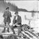 Tre män har matpaus ute på vintern. 1900-talets första hälft.
